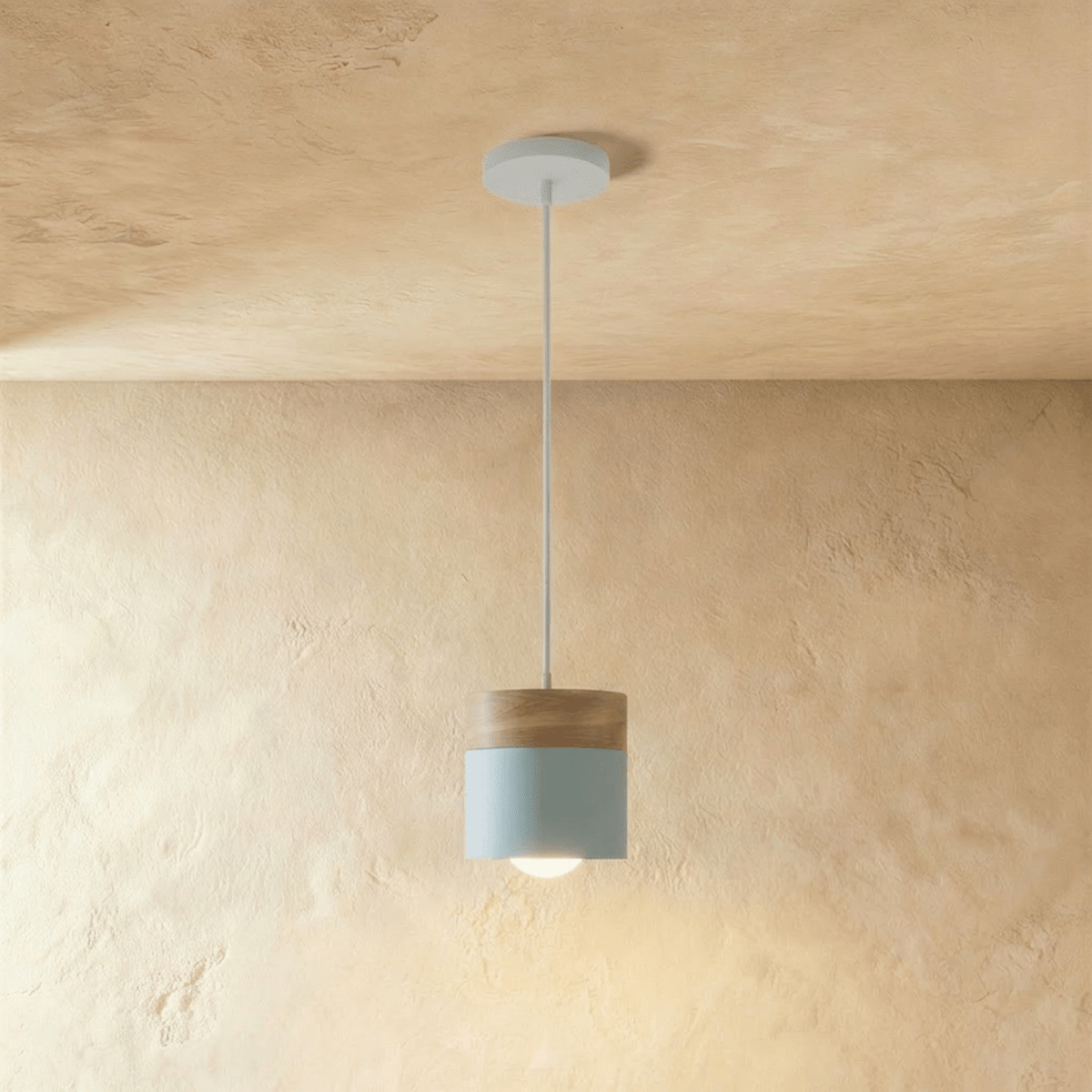 Clérachic pendant light with a light blue cylinder shade and walnut cap, suspended from a plain plaster ceiling.