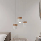 Clérachic white pendant lights, three staggered over a side table beside a beige sofa and round mirror.