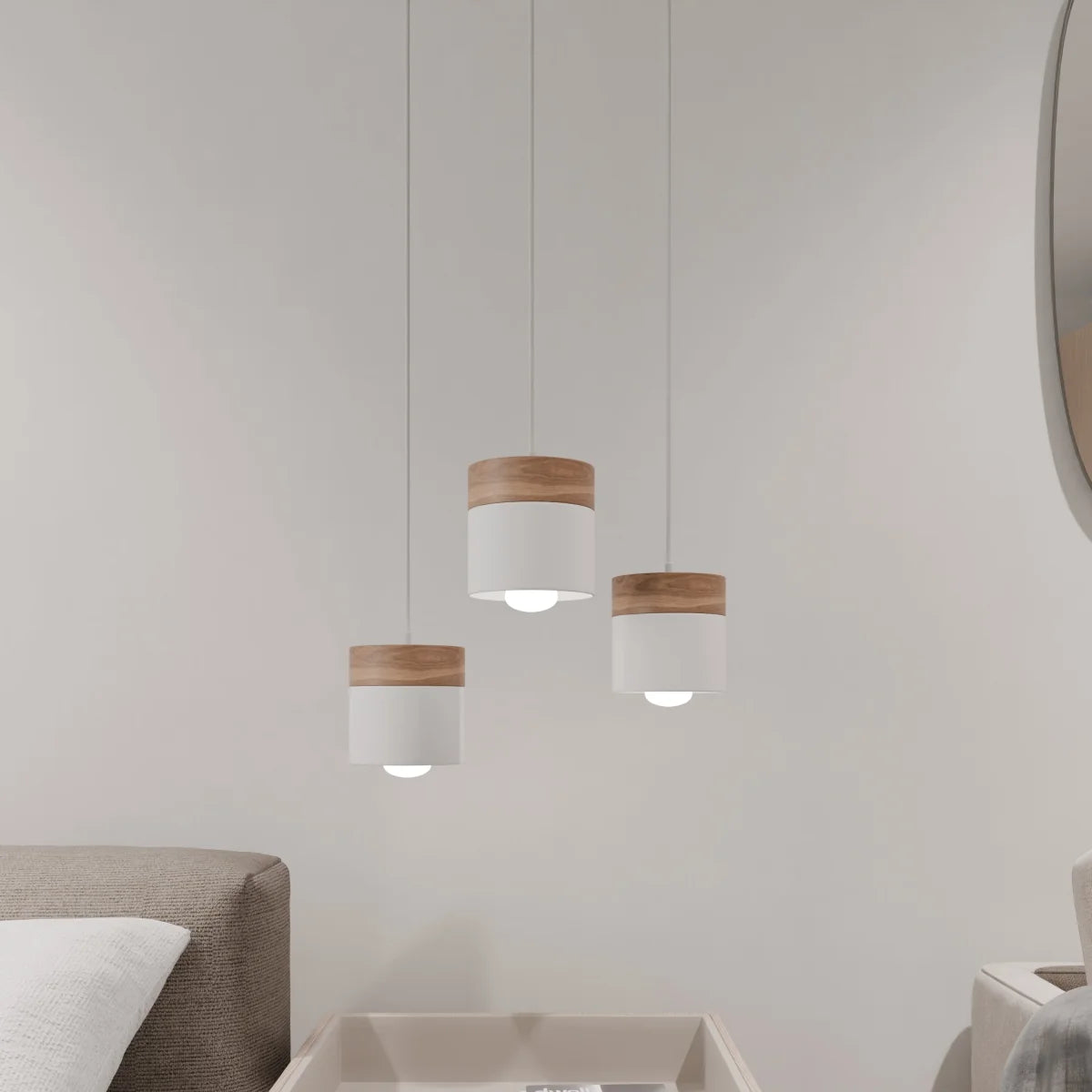Clérachic white pendant lights, three staggered over a side table beside a beige sofa and round mirror.