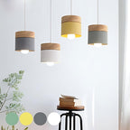 Clérachic wood-top pendant lights in grey, white and yellow, staggered above a stool stacked with books.