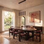 Clérachic five-pendant black light fixture hangs above a dining table beside an arched window and garden view.