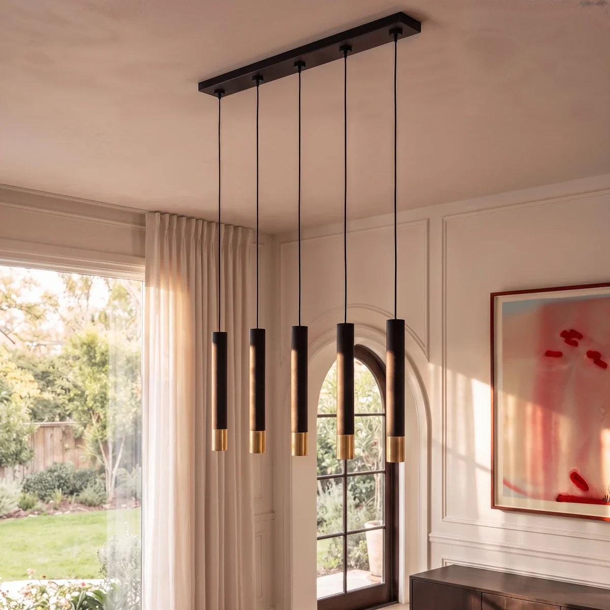 Clérachic black pendant cluster with gold rim tips lights a dining nook framed by sheer curtains and a doorway.