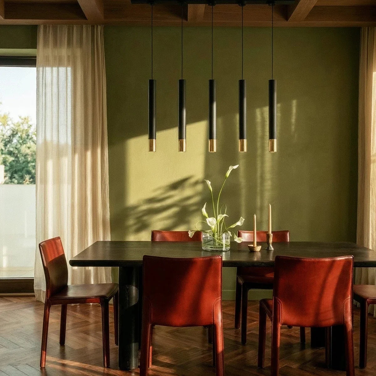 Clérachic five-pendant black light fixture hangs over a dark dining table with red leather chairs and olive walls.