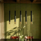 Clérachic black pendant cluster with gold rim tips lights a table set with lilies and candles against a green wall.