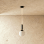 Clérachic black metal pendant light with a glossy white globe shade, suspended from a round ceiling canopy.