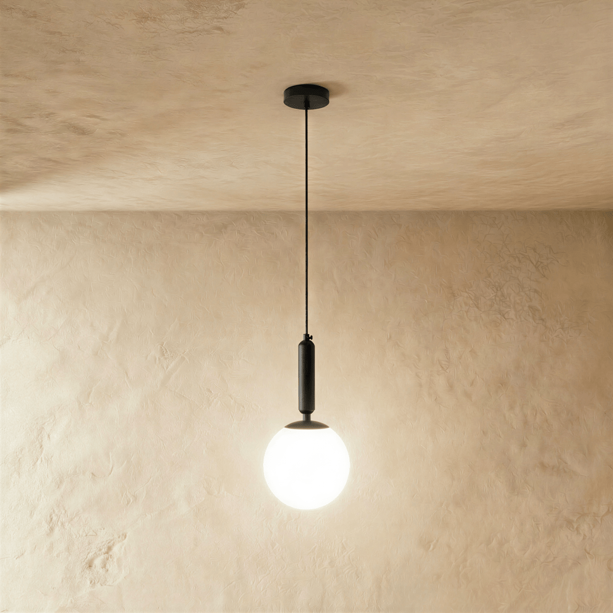 Clérachic black metal pendant light with a glowing white globe shade against a plaster wall and ceiling.
