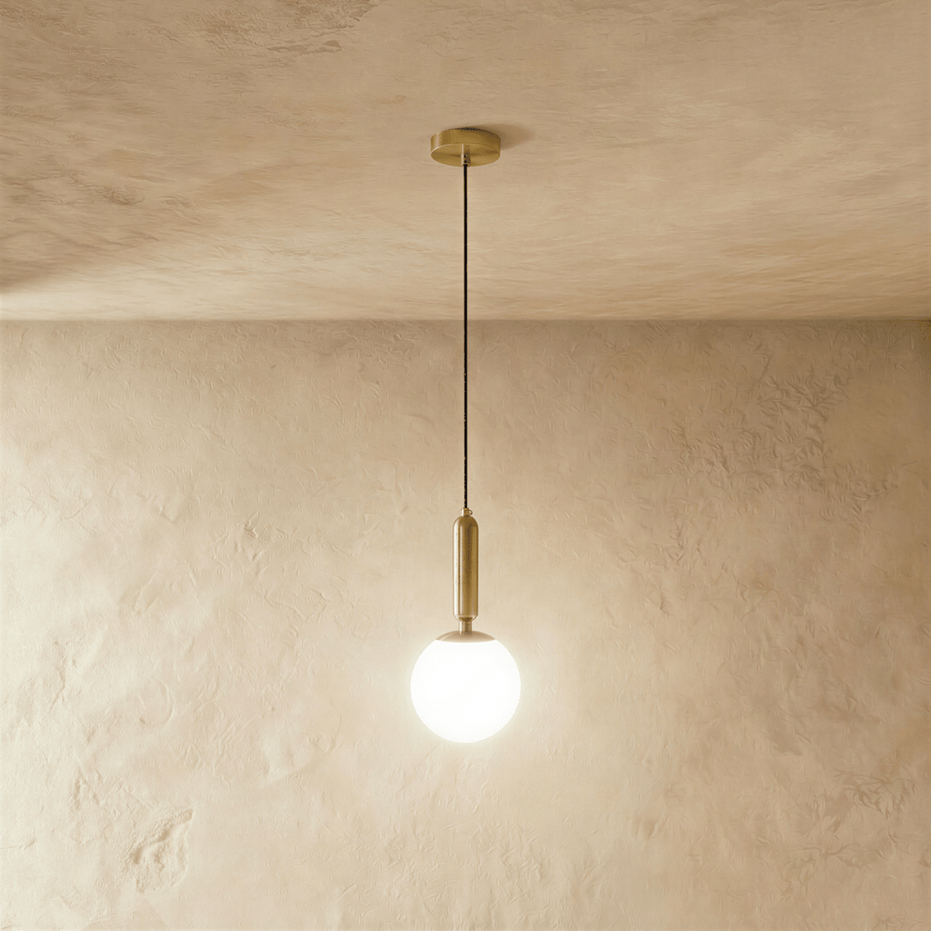 Clérachic brass pendant light with a glowing white globe shade, suspended from a round brass ceiling canopy.