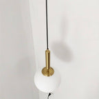 Clérachic brass pendant light in close detail, showing the fluted brass socket housing above a white globe shade.