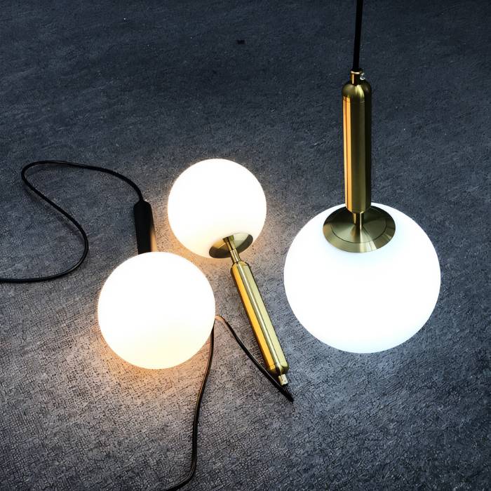 Clérachic pendant light components laid out, showing the brass and black fittings, cords and white glass globes.