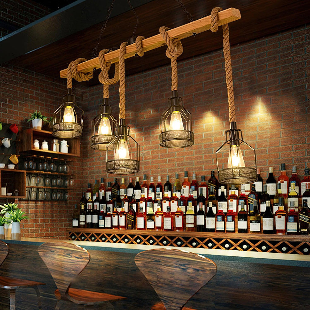 Clérachic pendant light with rope-hung cages lit above a brick-backed bar, with rows of bottles on the shelves behind.