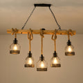 This Clérachic pendant light switched on beneath a beige ceiling, its five filament bulbs glowing inside black mesh cages.