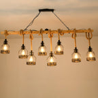A longer Clérachic pendant light with eight lit caged bulbs hanging at staggered heights from a wooden beam under a warm ceiling.