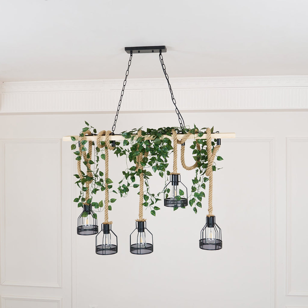 A Clérachic pendant light dressed with trailing green ivy along the beam, shown against a white panelled wall.