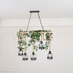 A Clérachic pendant light dressed with trailing green ivy along the beam, shown against a white panelled wall.