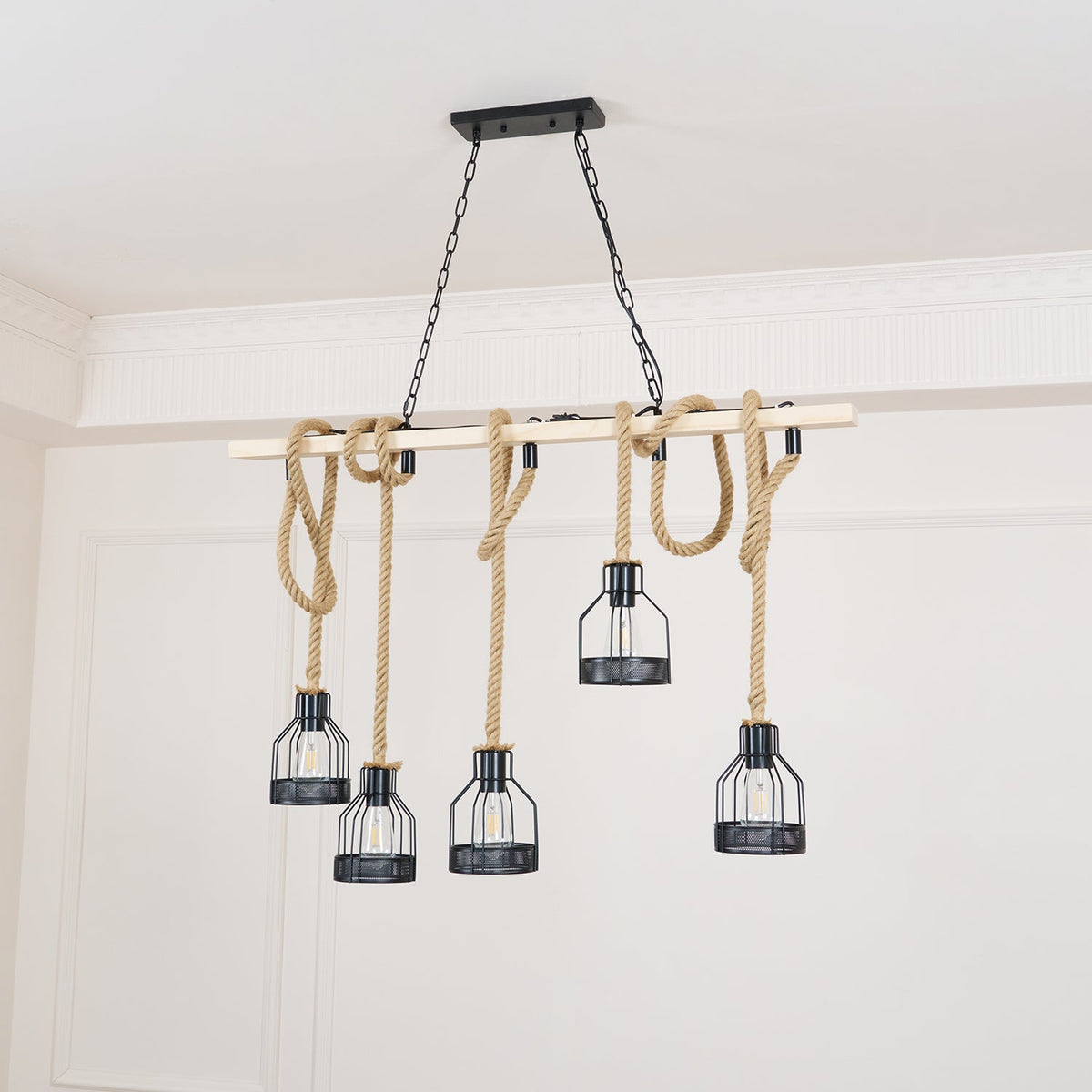 Unlit Clérachic pendant light with a pale wooden beam and five black cages on rope drops, in a white panelled room.