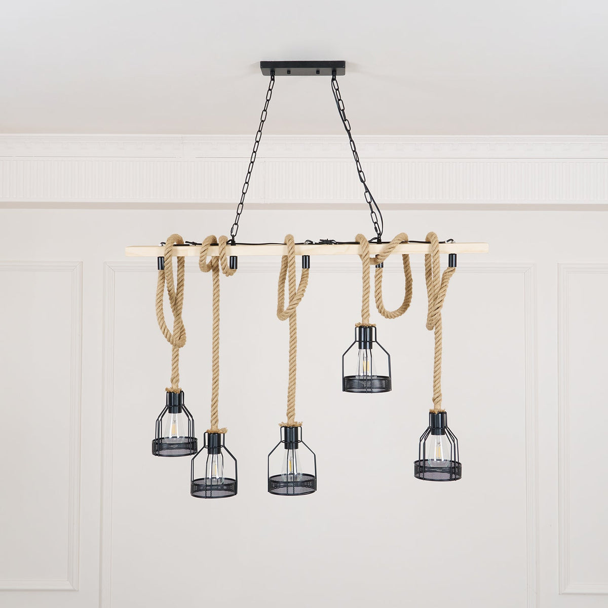 A pale-beam Clérachic pendant light with five rope-hung cages, shown from a slightly lower angle in a white room.