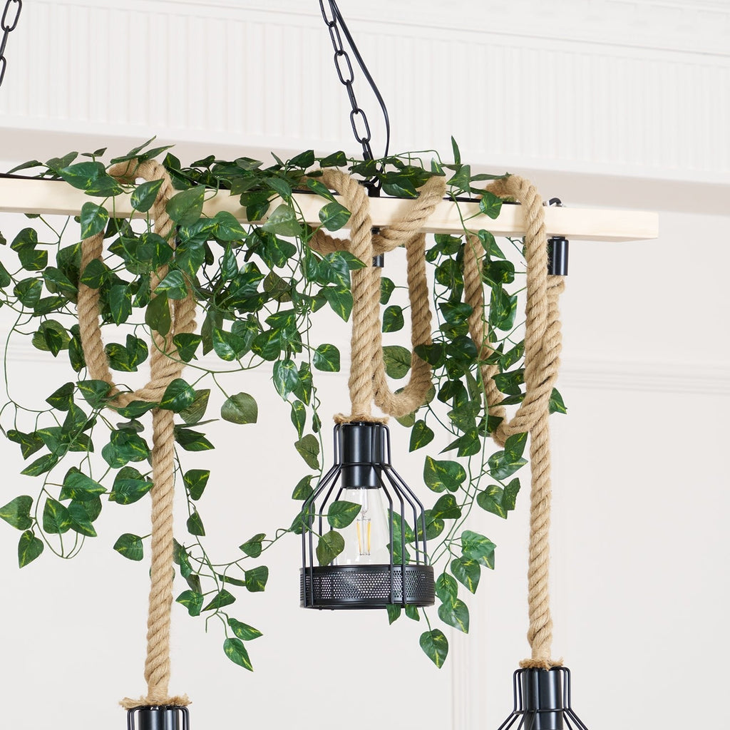 Clérachic pendant light seen close up, with green leaves trailing over the rope loops and a black cage hanging below.