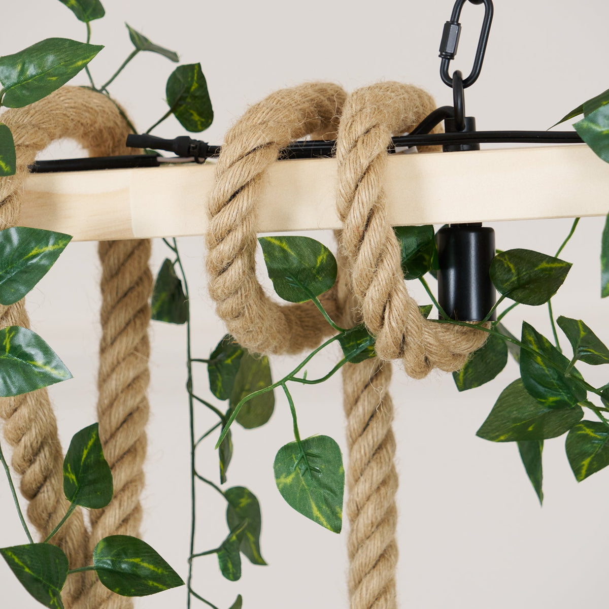 Close view of the pale beam, the thick hemp rope loops and the chain clip on this Clérachic pendant light, with leaves around.