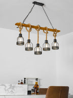 This Clérachic pendant light on a wooden beam, seen from a low angle, with a marble counter and a glass of whisky below.
