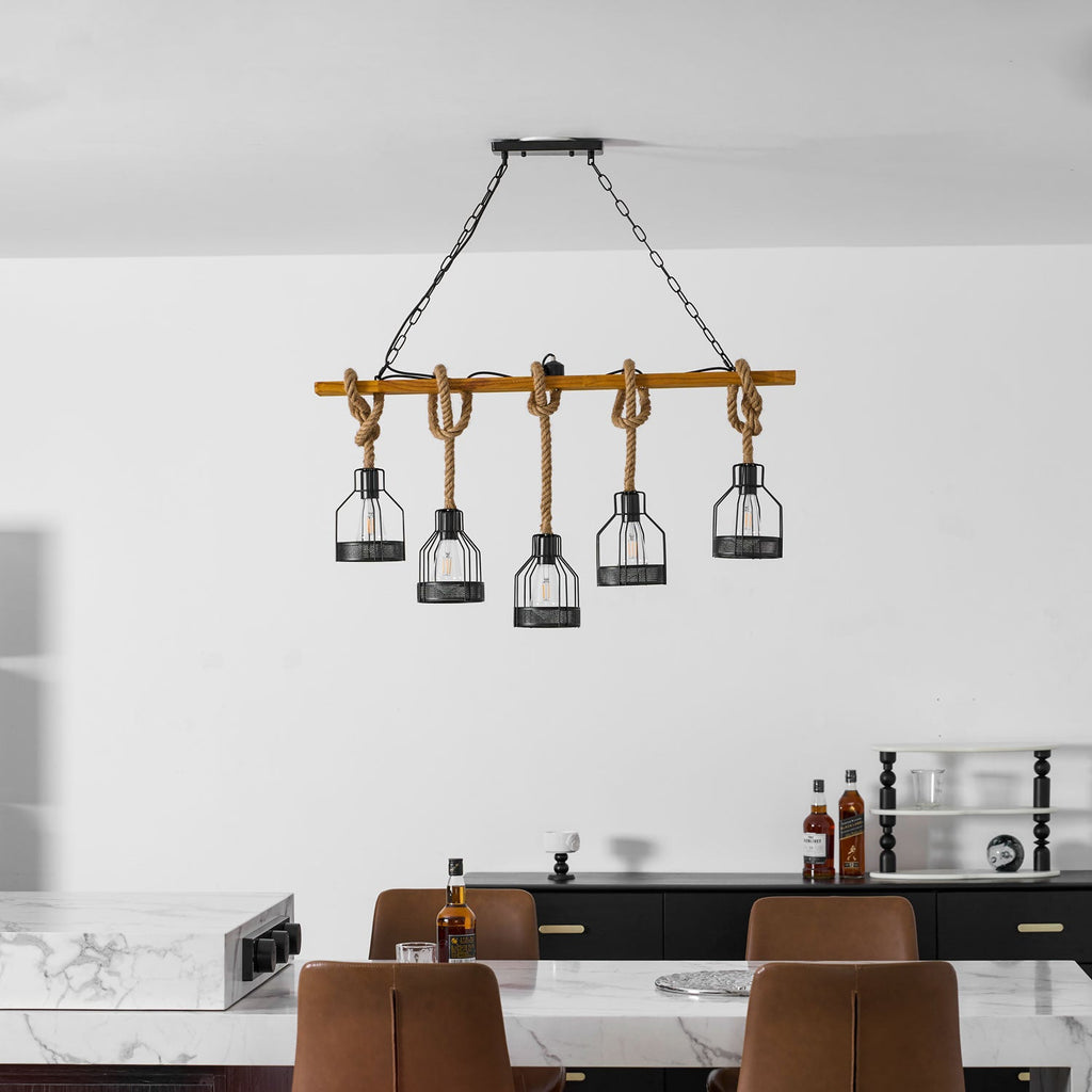 A Clérachic pendant light hung high above a marble counter, with leather chairs and a black sideboard below it.