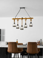 This Clérachic pendant light seen from across a white kitchen, above a marble counter and two leather dining chairs.