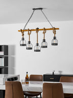 A Clérachic pendant light at the top of a white wall, with a marble counter, chairs and a bottle of whisky below.