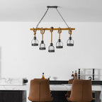 Clérachic pendant light centred above a marble-topped island and tan chairs, with a sideboard and bottles behind.