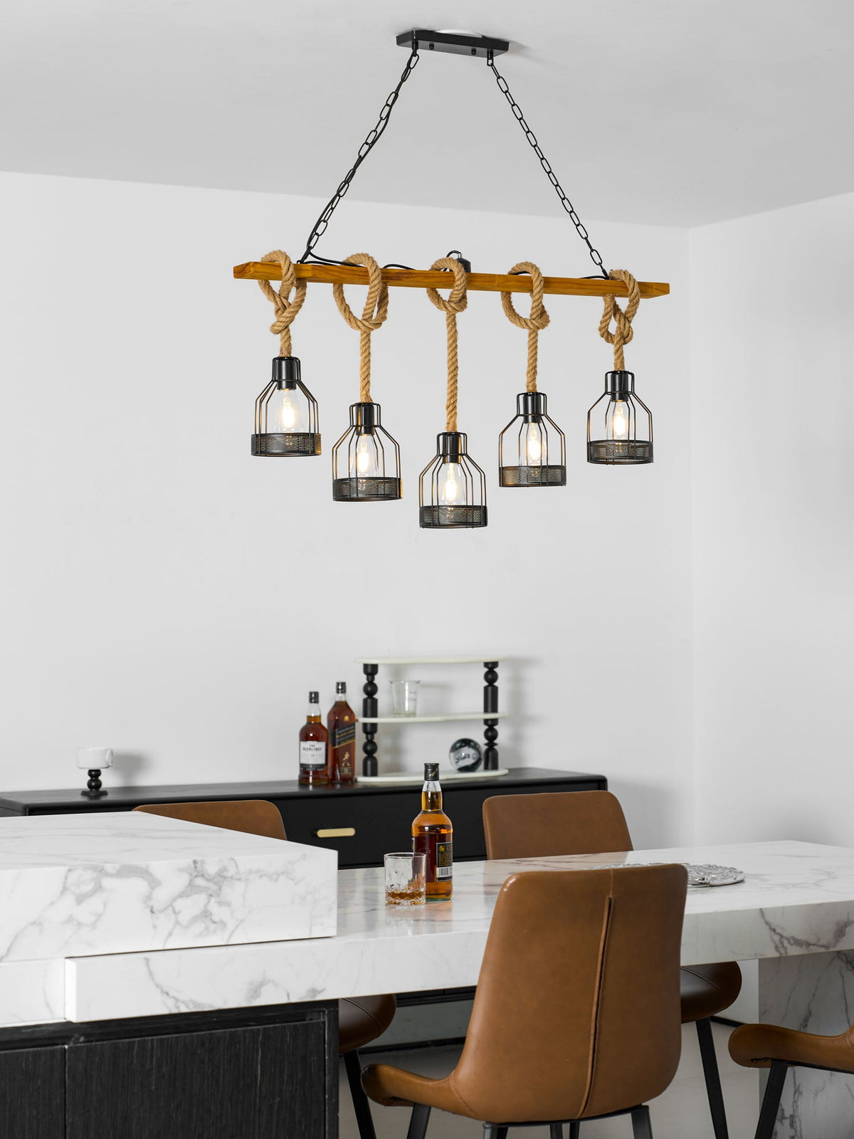 Clérachic pendant light shown narrower in the frame, above a marble counter, tan chairs and a bottle of whisky.