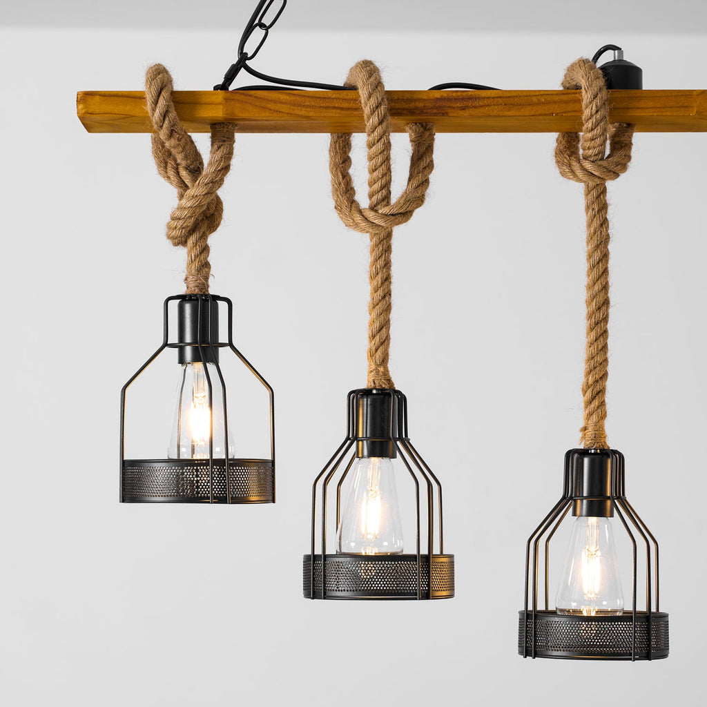Close view of three black mesh cages with clear filament bulbs hanging on knotted hemp rope from a Clérachic pendant light.