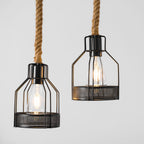 Close view of two black iron cages with clear filament bulbs, each on a length of thick hemp rope on this Clérachic pendant.