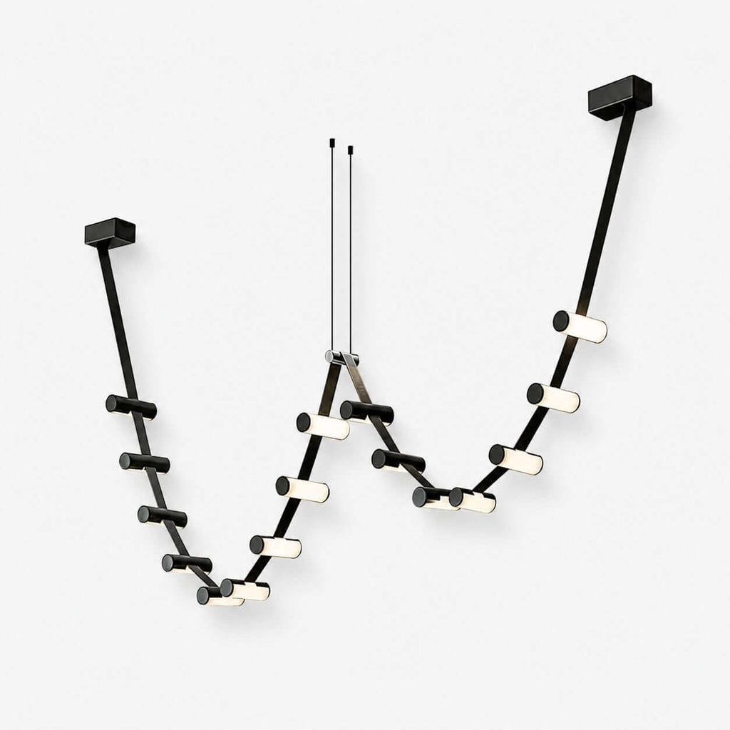 A Clérachic linear pendant light in black, with small glowing cylinders along a looping run hung from two ceiling plates, on white.