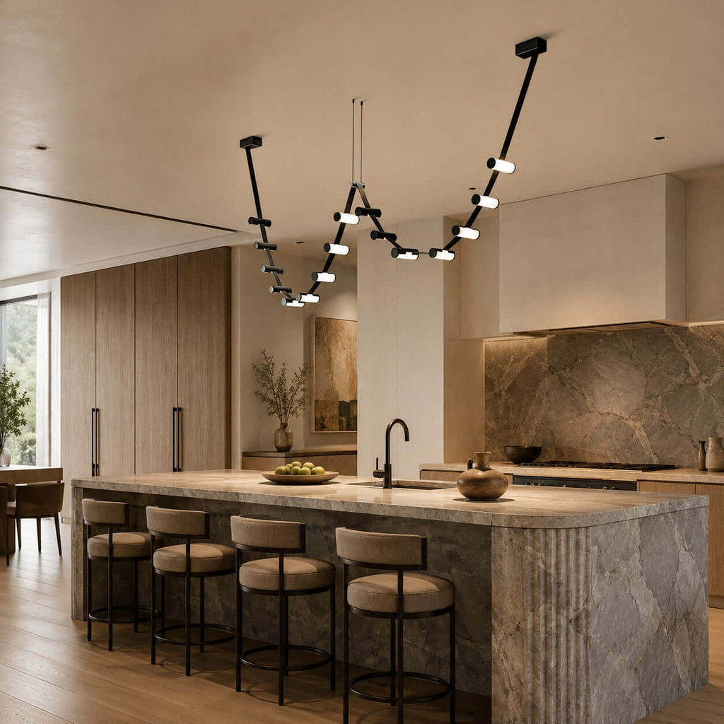 Black Clérachic linear pendant draped in two loops above a stone-clad kitchen island with leather-topped bar stools.