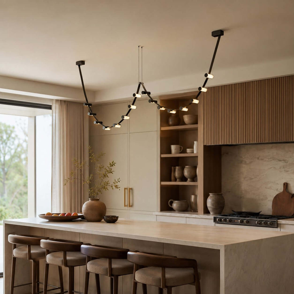 This Clérachic black pendant light swoops across a kitchen above a pale island, with open shelving and a wide window beside it.