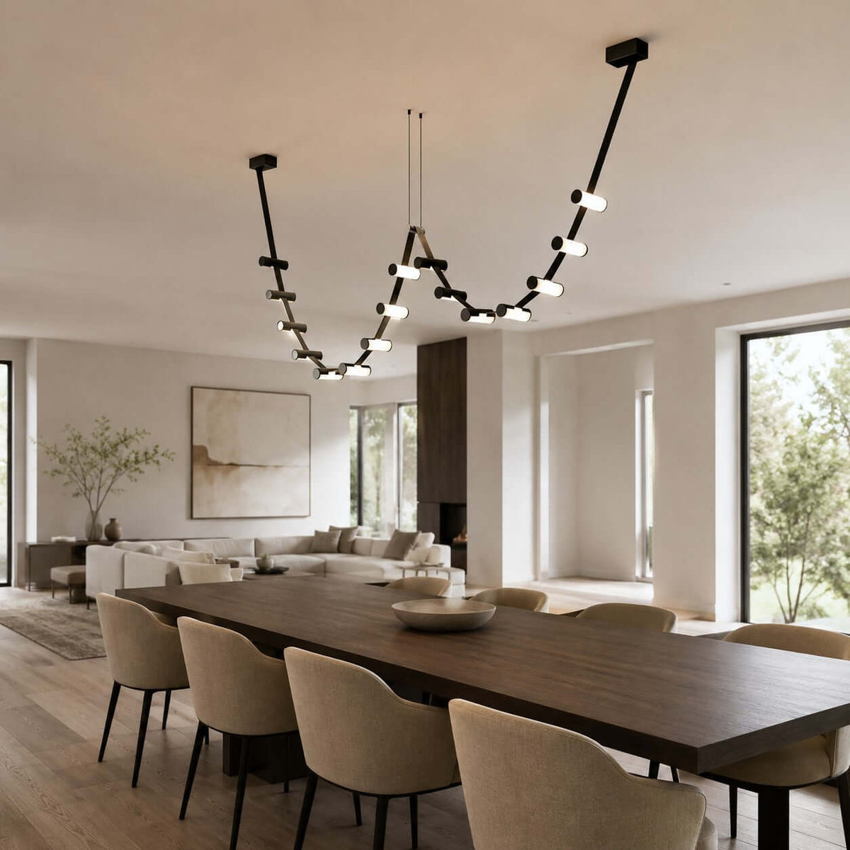 Over a long dark dining table in an open-plan room, a Clérachic linear pendant dips in two loops of lit cylinders.