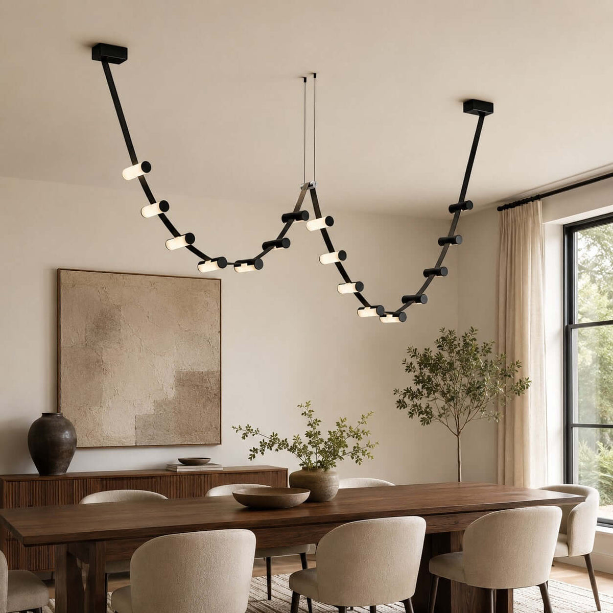 This Clérachic black linear pendant hangs above a walnut dining table, with a sideboard and an olive tree behind.