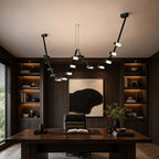 Clérachic black linear pendant in a dark study with built-in lit shelves, a wide wooden desk and a large abstract print.