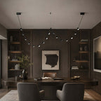 Beaded Clérachic pendant light hung across a dark panelled room above a curved wooden table and two grey armchairs.