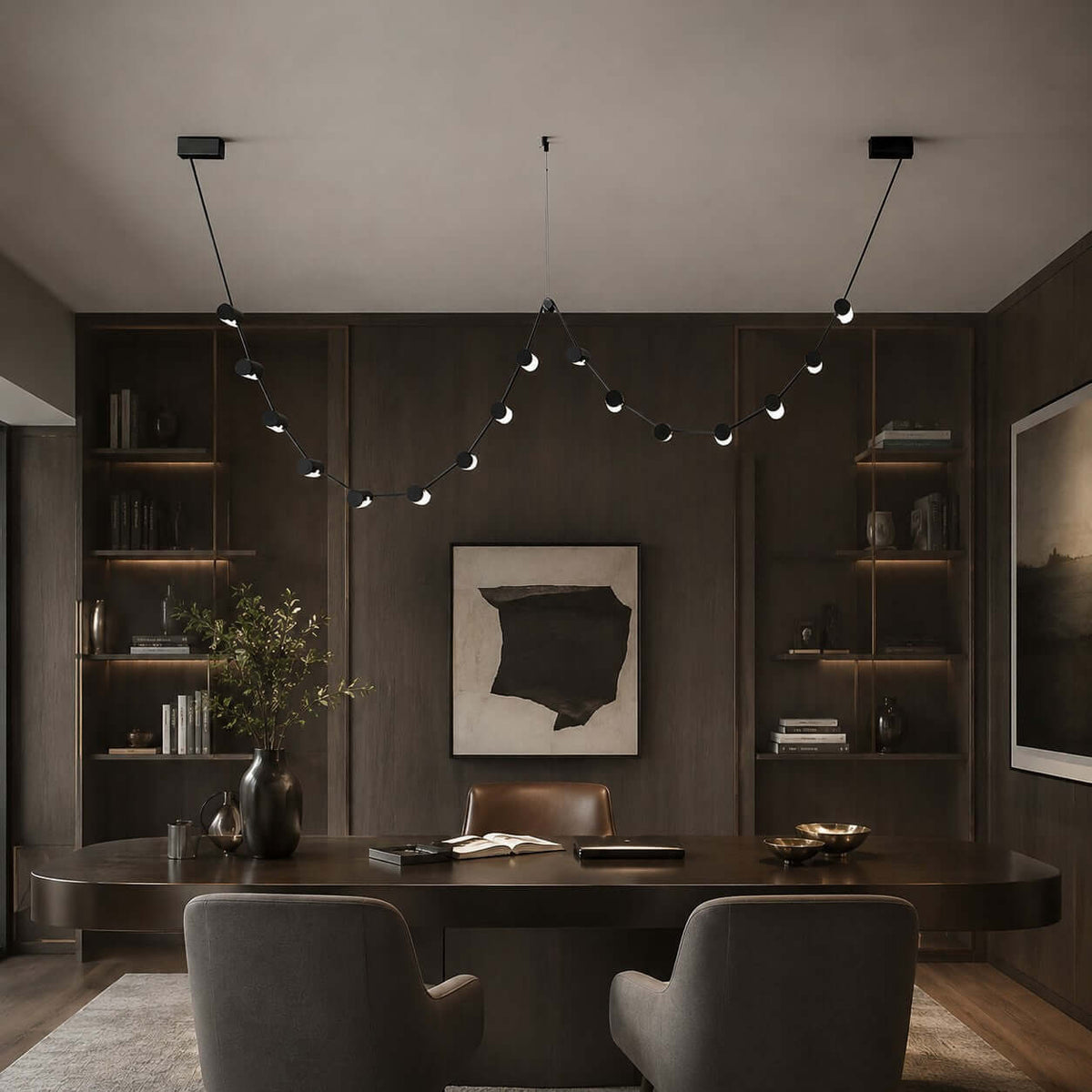 Beaded Clérachic pendant light hung across a dark panelled room above a curved wooden table and two grey armchairs.