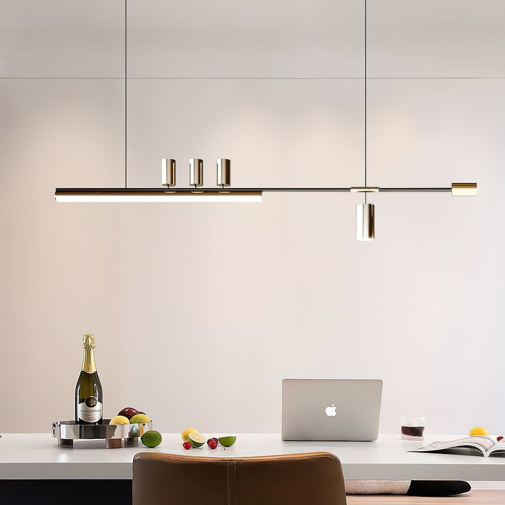 Slim lit bar of this Clérachic pendant hung over a white dining table with a laptop, a bottle and fruit below.