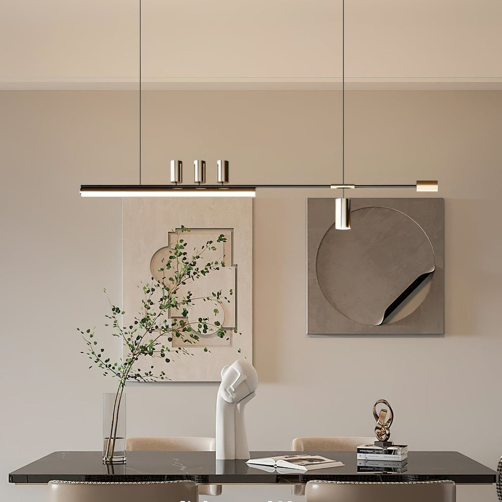 This Clérachic pendant runs above a black-topped dining table, with a leafy branch and abstract wall art behind it.