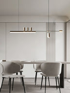 This Clérachic pendant hangs in a pale dining room, centred over a long table with grey upholstered chairs.