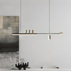 Long bar of this Clérachic pendant lit in front of a grey wall and a textured abstract canvas, with a dark sculptural piece below.