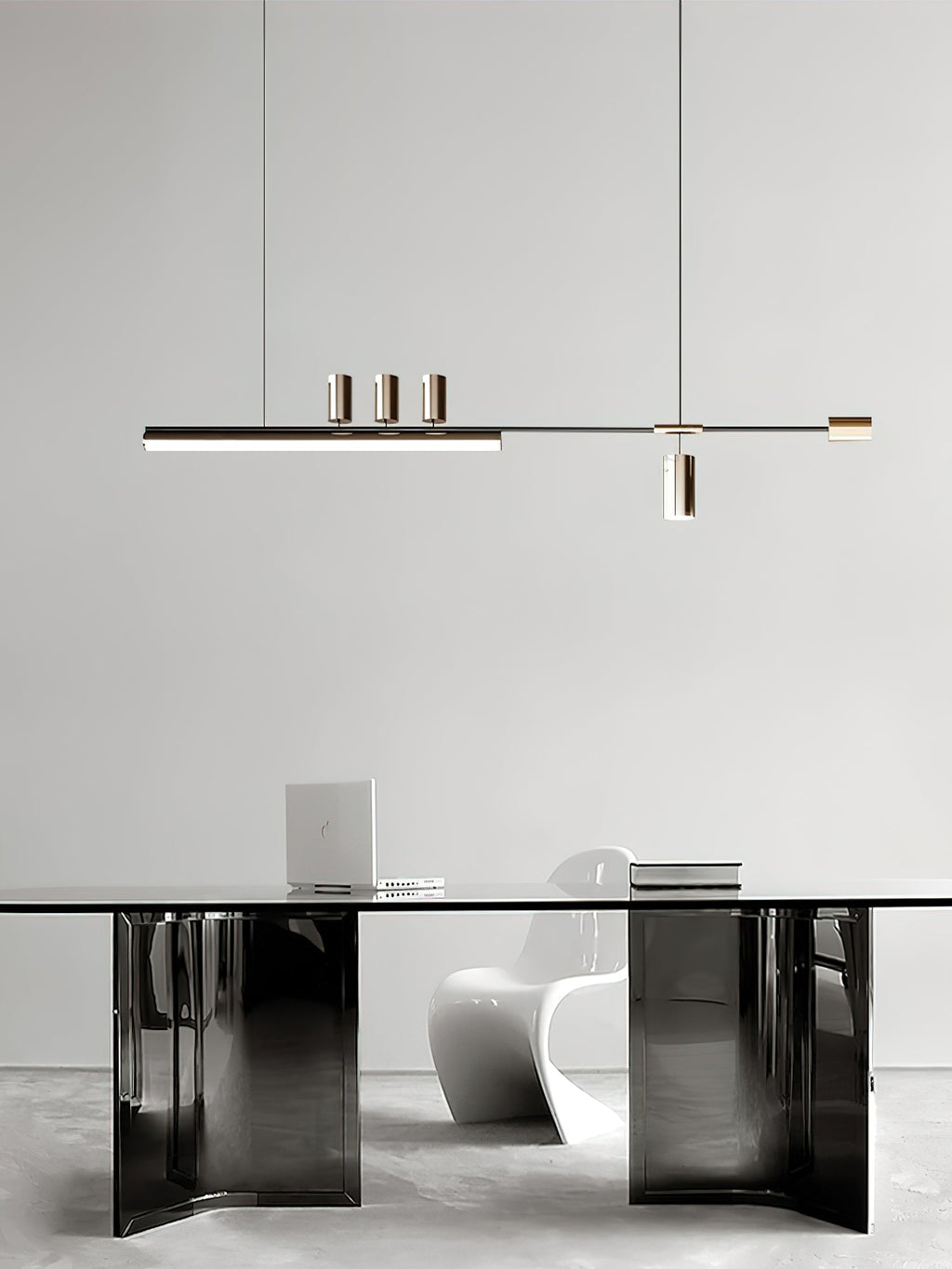 This Clérachic pendant hangs over a glossy dark-based table with a white sculptural chair and a laptop on top.