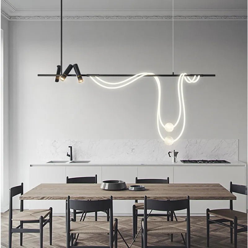 Clérachic black bar pendant with spot heads and a looping LED tube holding two glowing spheres, in a grey dining room.