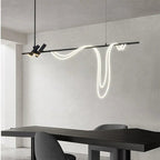 Clérachic black bar pendant with two angled spot heads and a looping white LED tube over a dark table in a pale room.