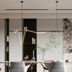 Clérachic black bar pendant with a looping LED tube and three spot heads, hung in a room with a dining table and shelving.