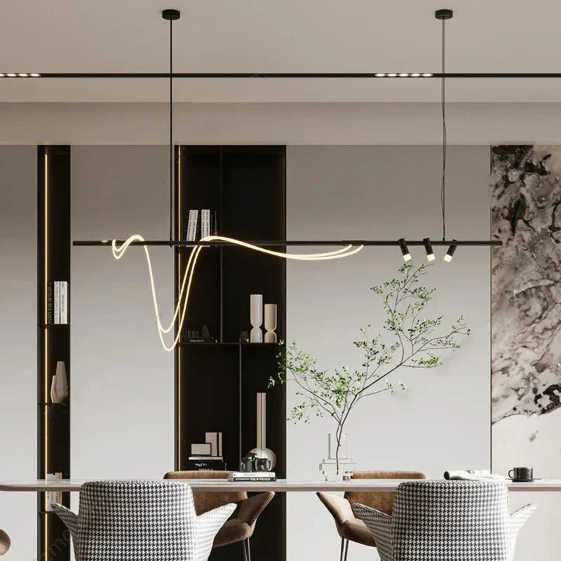 Clérachic black bar pendant with a looping LED tube and three spot heads, hung in a room with a dining table and shelving.