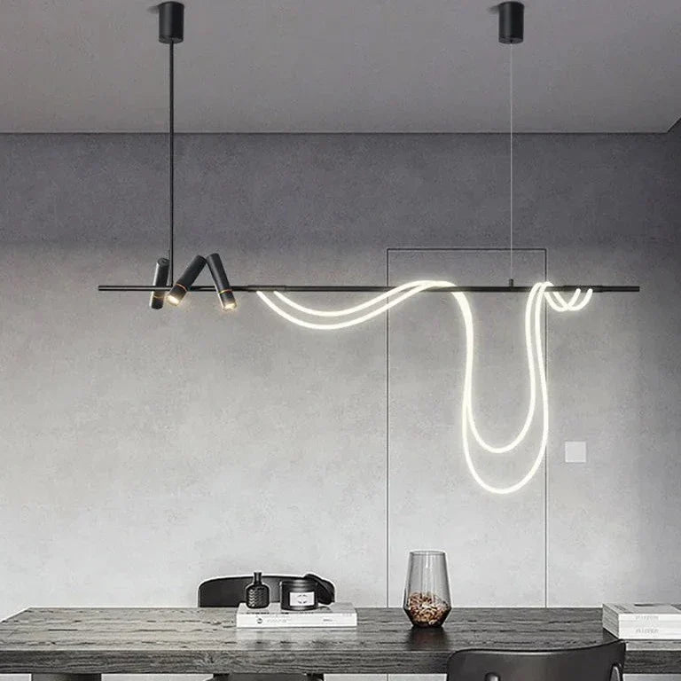 Clérachic black bar pendant on two cables with a looping white LED tube and spot heads, in a grey room above a dark table.