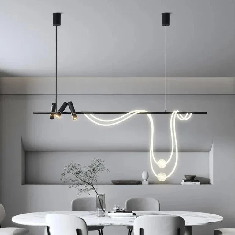 Clérachic black bar pendant with a looping LED tube and two glowing spheres, hung above an oval marble dining table in a room.
