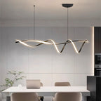 Clérachic twisting black LED pendant hung over a white dining table in a kitchen with panelled grey walls and a black marble island.